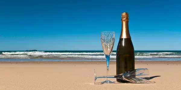 Bottle of champagne with two crystals glasses on a secluded beach.